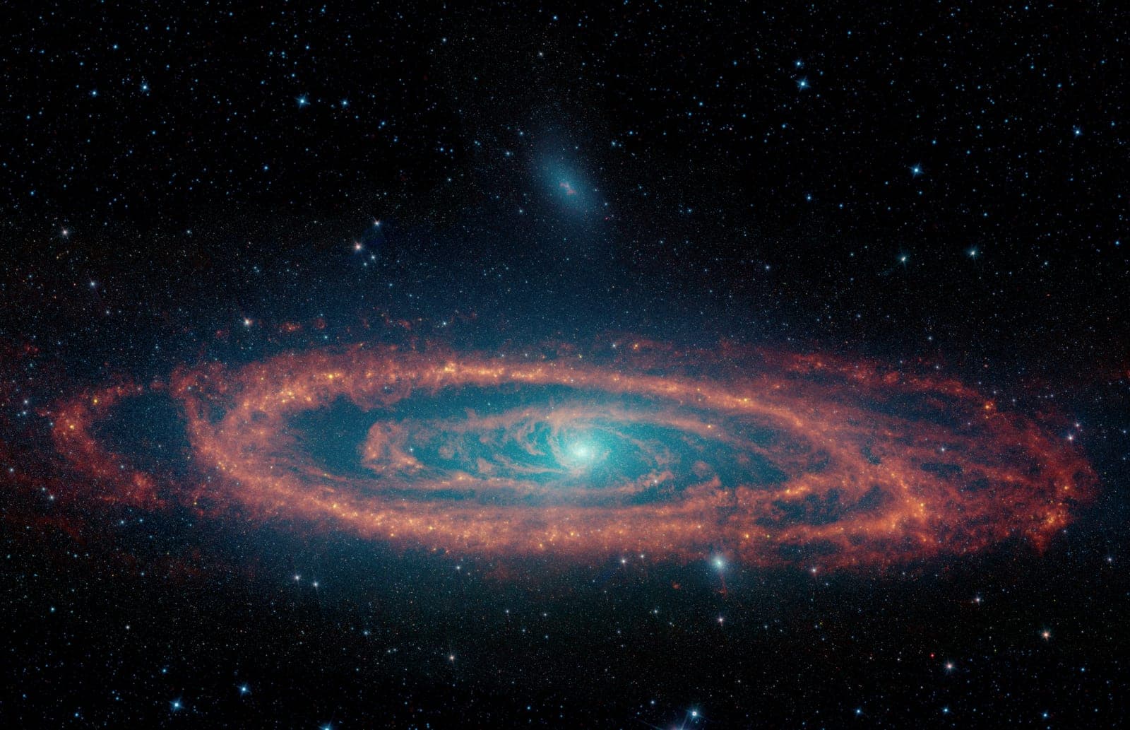 The Andromeda galaxy in infrared: orange rings of dust around a glowing blue core.