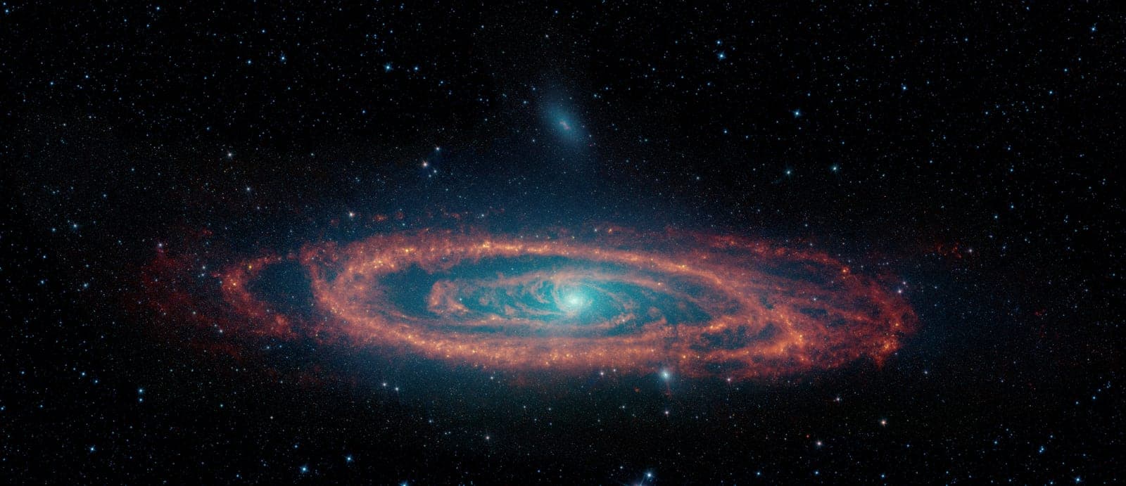 The Andromeda galaxy seen at a tilt: orange rings of dust around a glowing blue core, among blue stars.