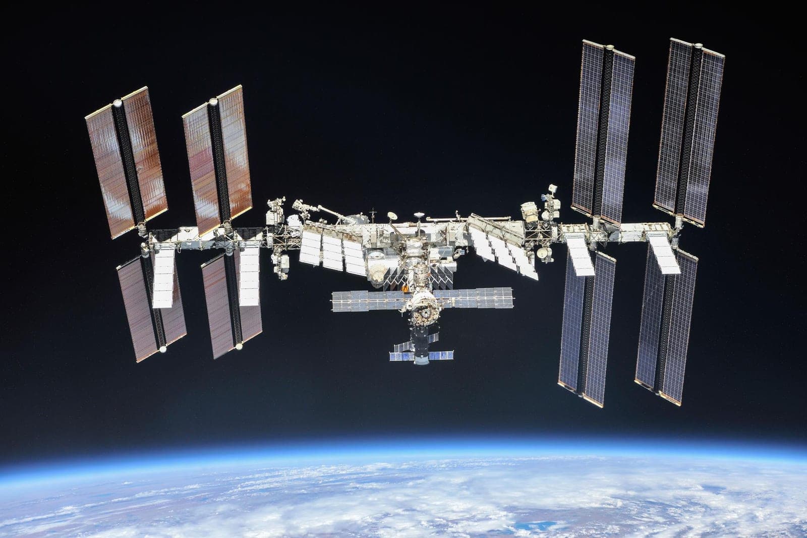 The International Space Station with its long solar panels above the blue curve of Earth.