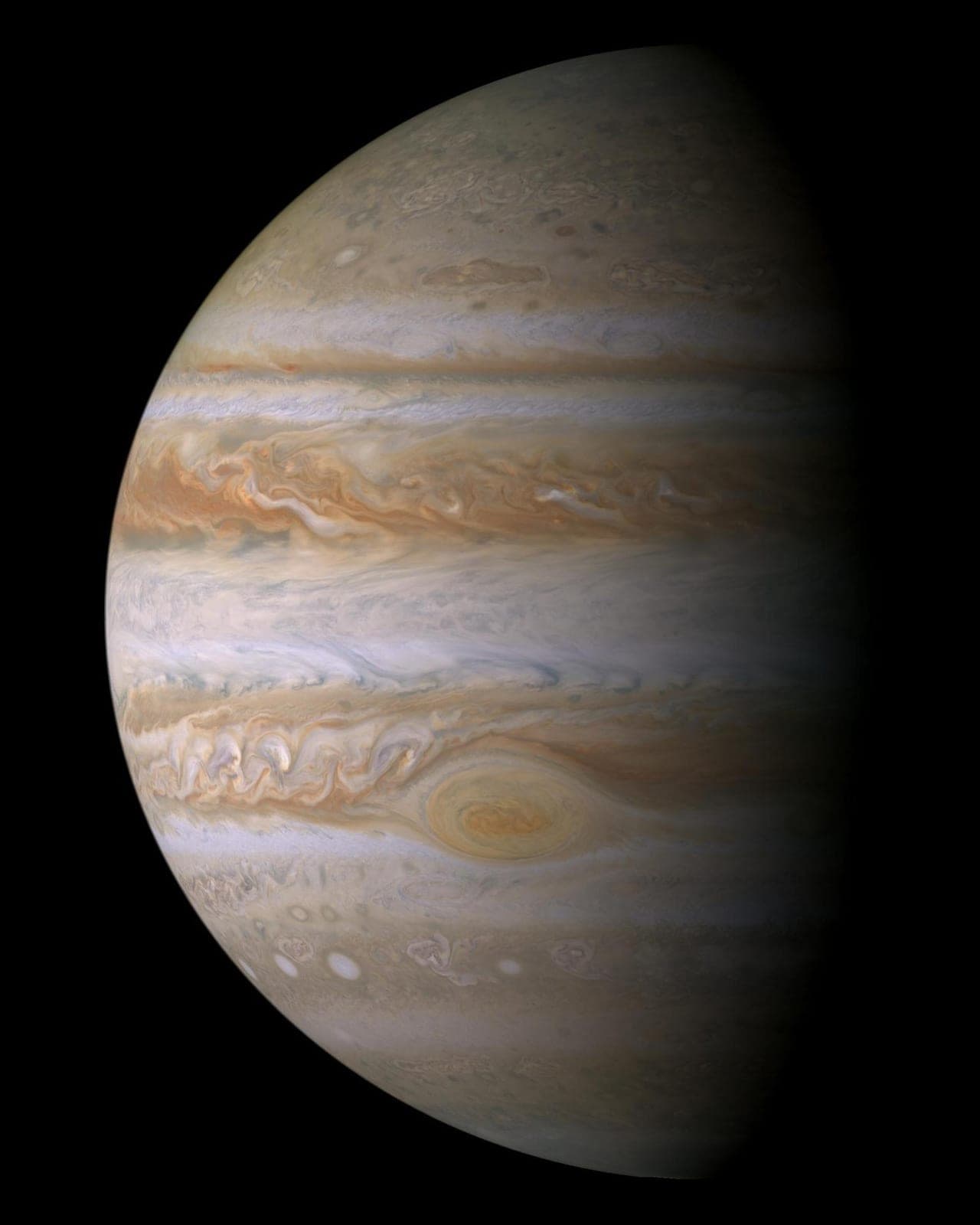 Jupiter's cream and brown cloud bands with the Great Red Spot, half in shadow.