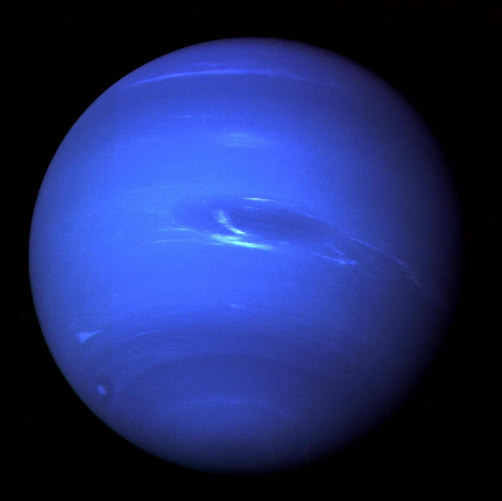 Deep blue Neptune with a dark oval storm and white streaks of cloud.