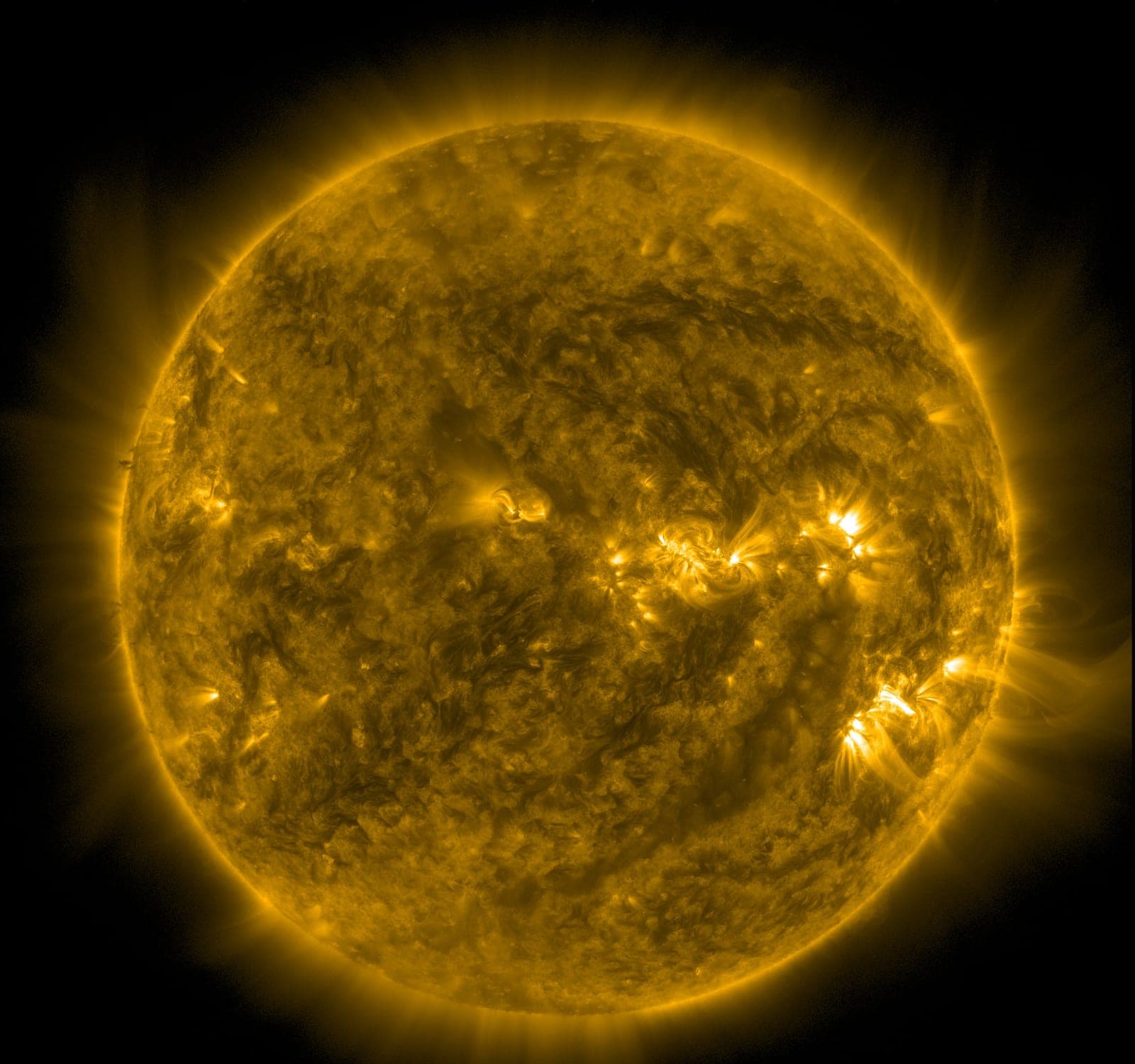 The Sun glowing gold, covered with bright loops and darker patches.