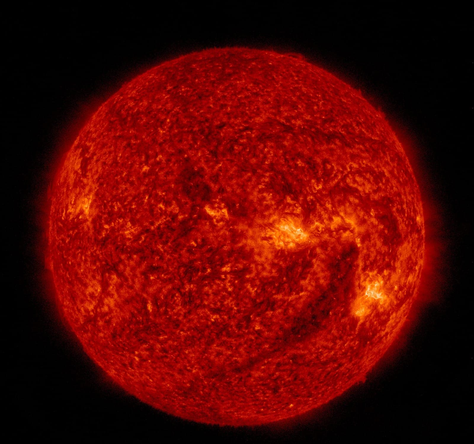 The Sun glowing deep red and orange with a grainy, mottled surface.