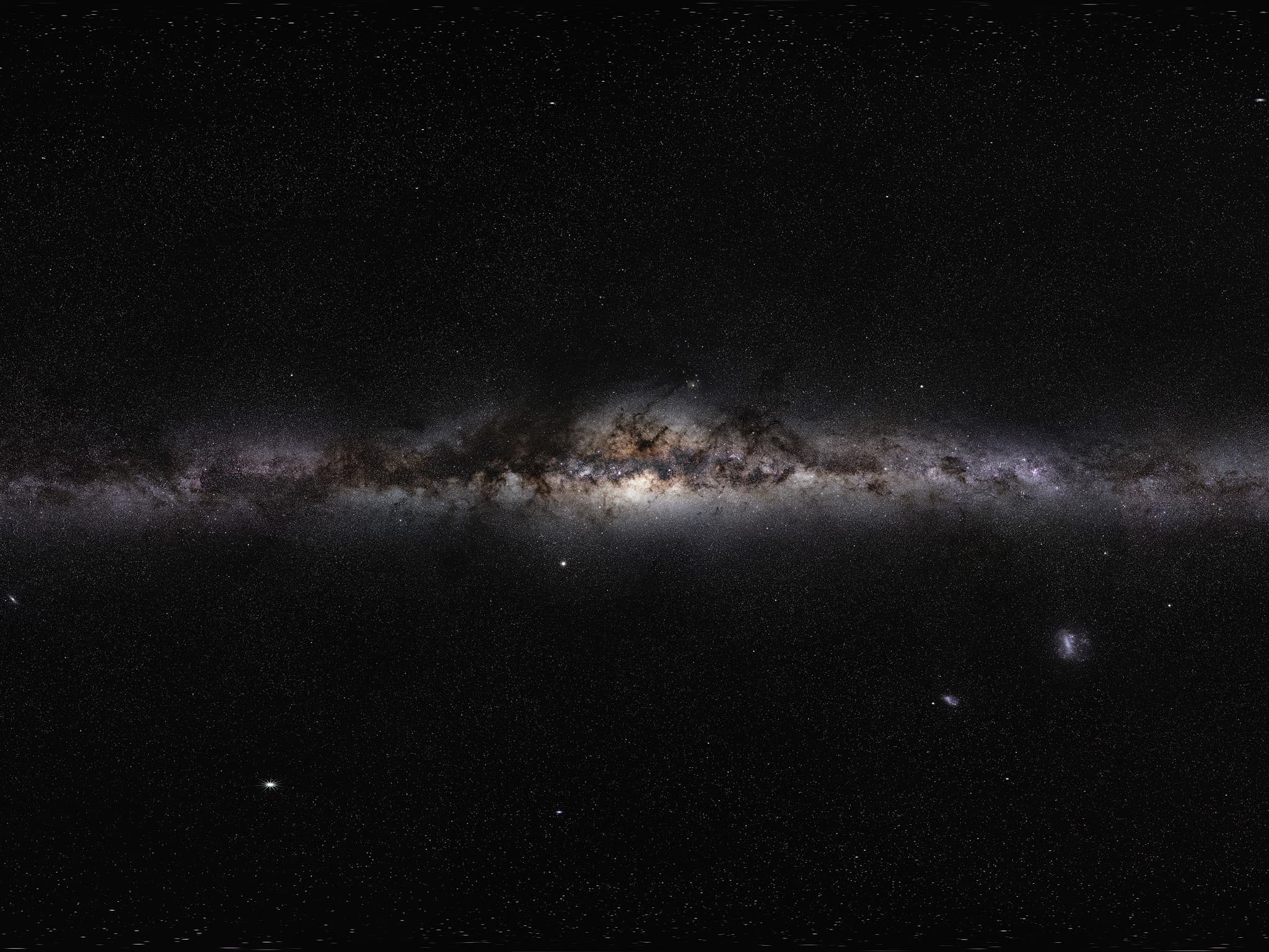 A band of countless stars and dark dust lanes crossing a black sky.